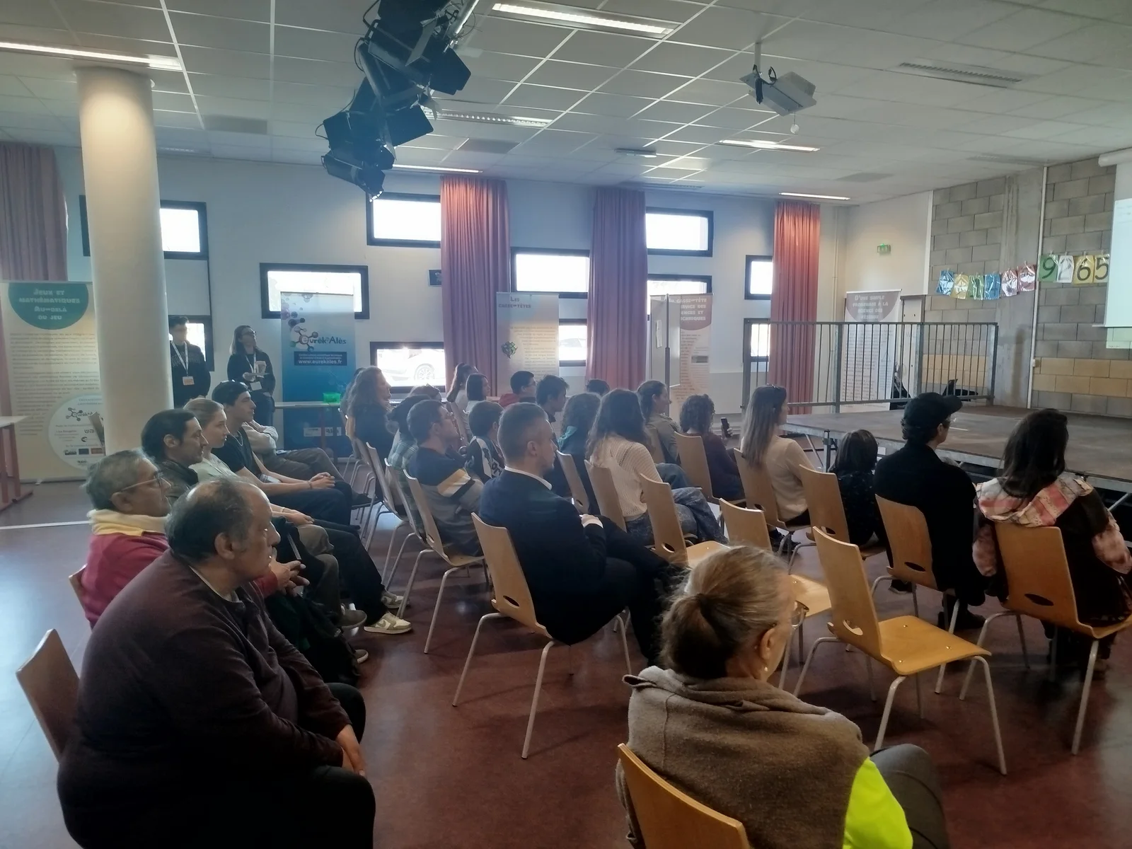 Le public assis en rangées face à la scène, dans la salle des conférences.